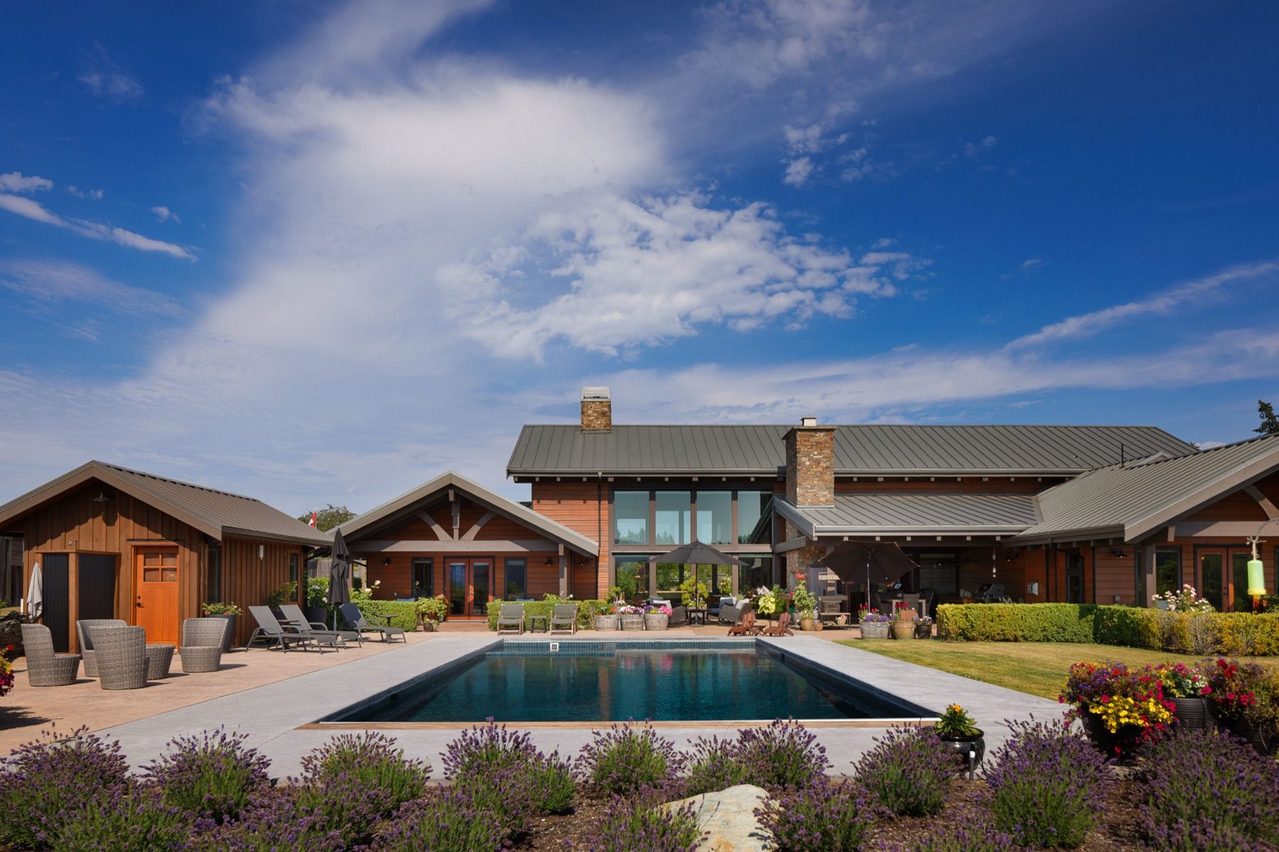 Pool and lavender garden in front of a ranch home under a blue sky