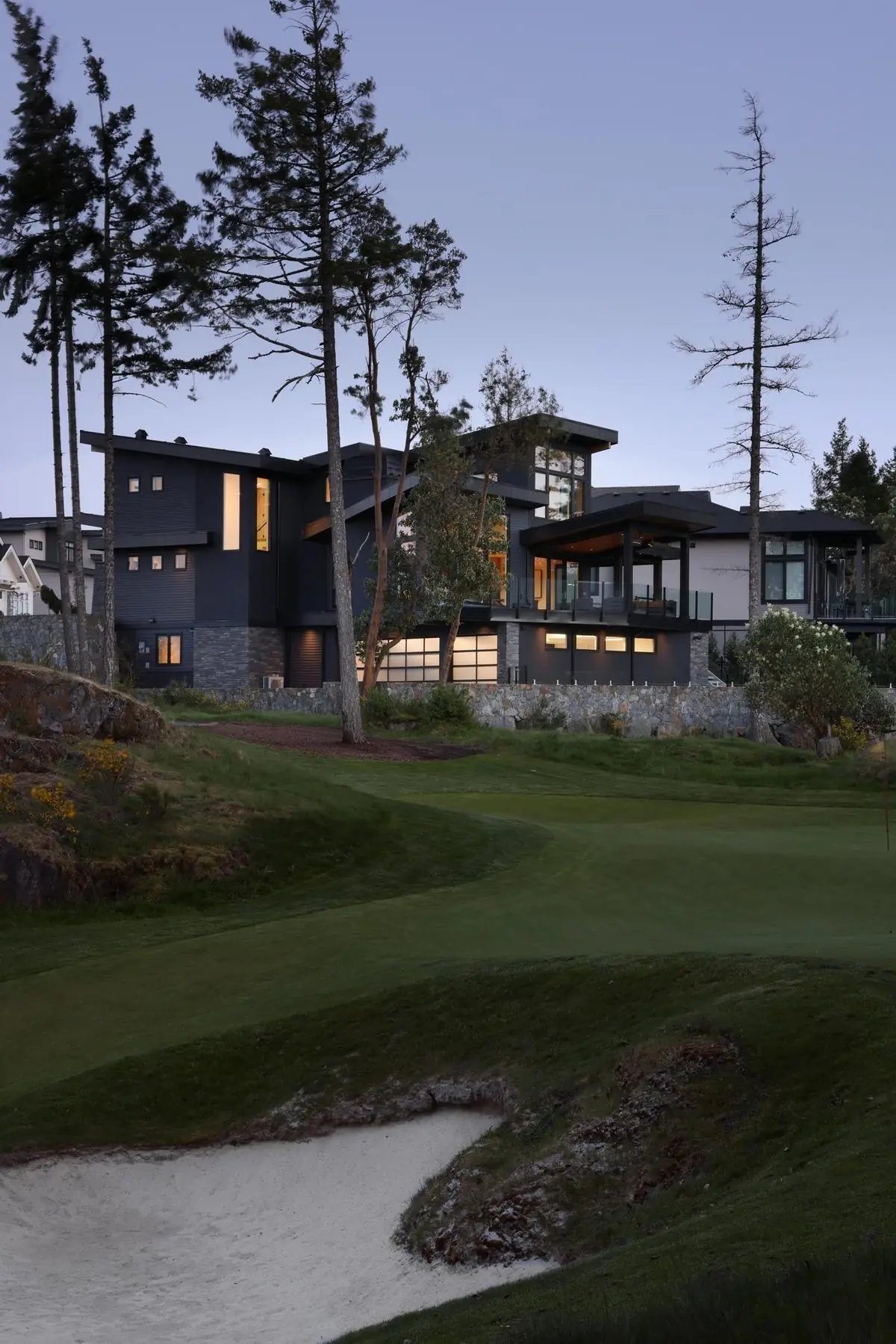 Contemporary home above a golf green at dusk