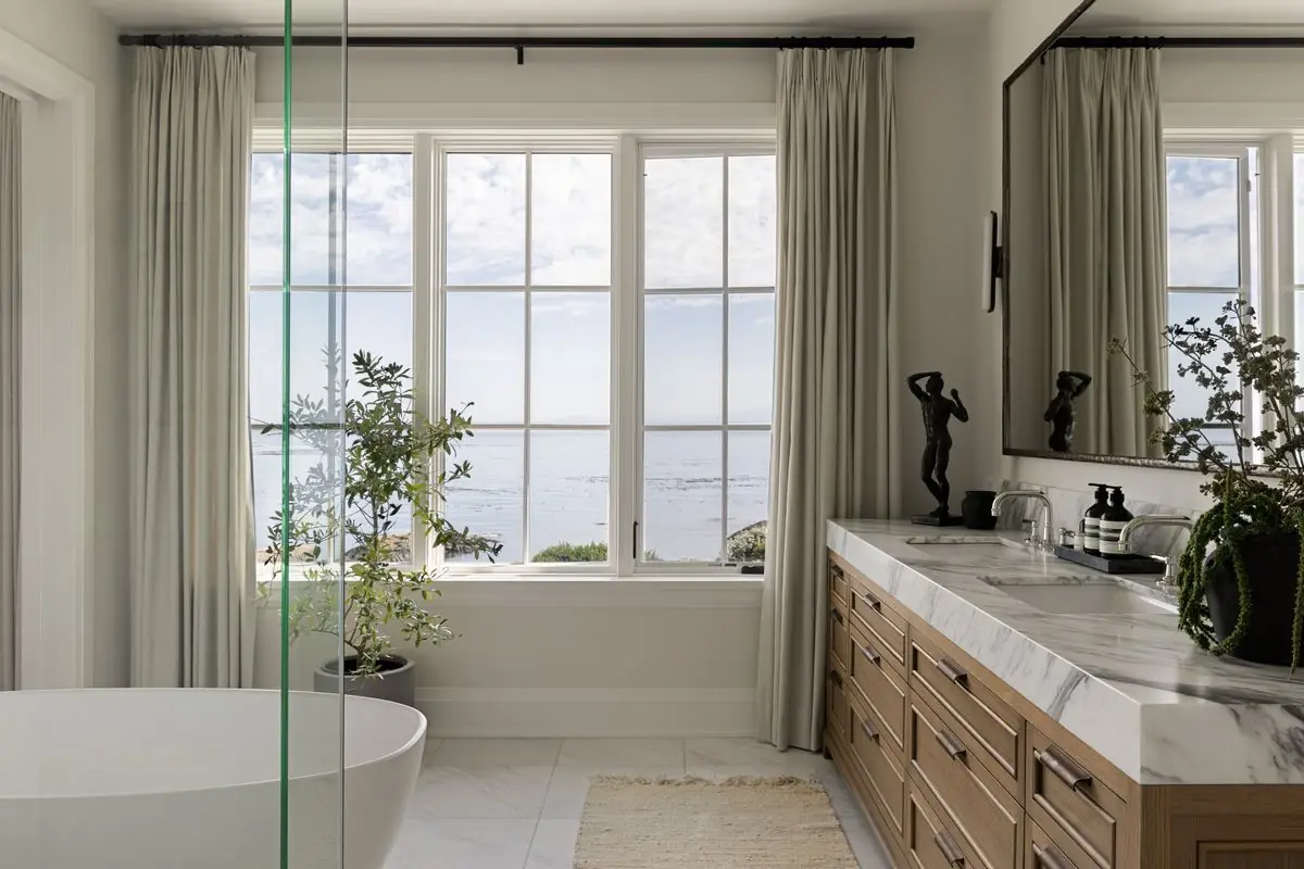 Tub and double vanity by windows onto the water
