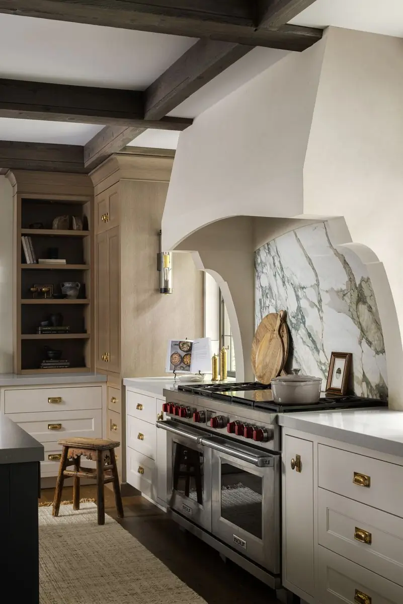 Range under a plaster hood and a marble backsplash