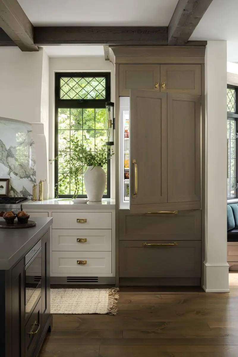 Oak-panelled refrigerator beside a leaded window