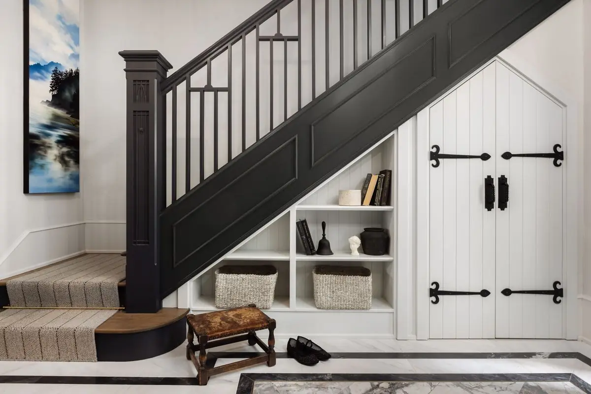 Black staircase with shelves and a strap-hinged door beneath