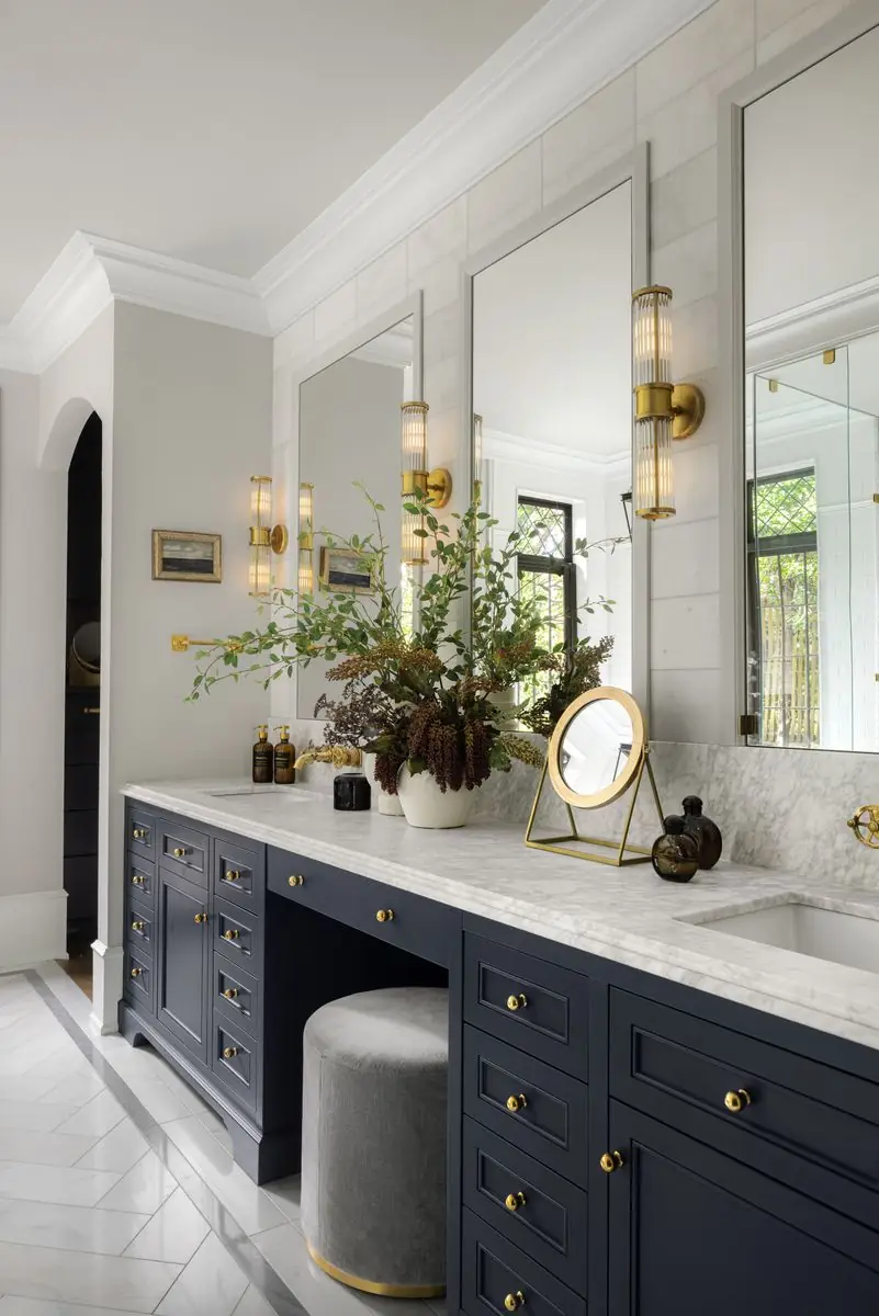Navy vanity with a marble top and brass sconces