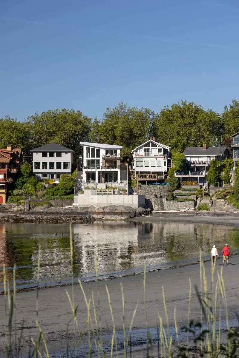The house from across the water, walkers on the beach below