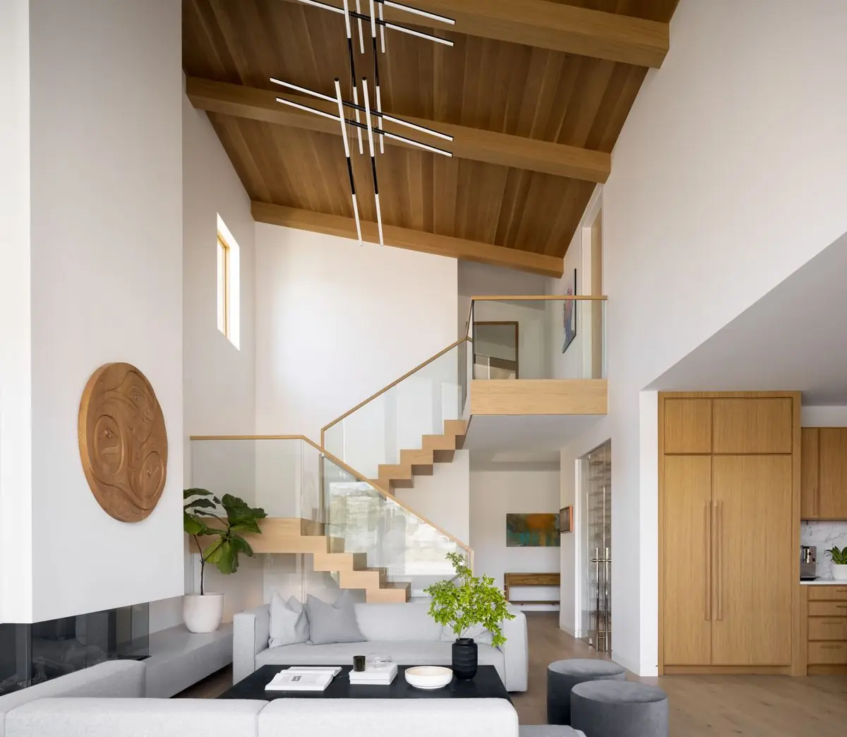 Oak and glass stair rising past the fireplace wall