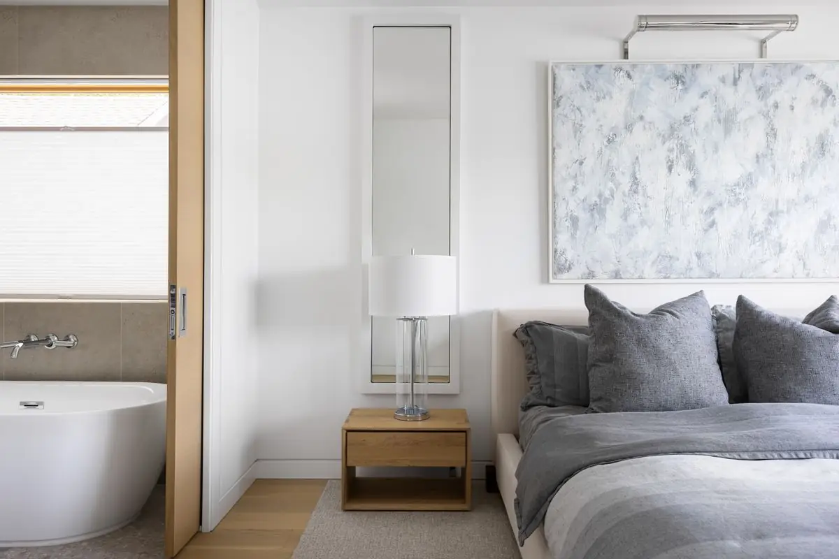 Bedroom with a pale abstract painting, the ensuite tub beside it