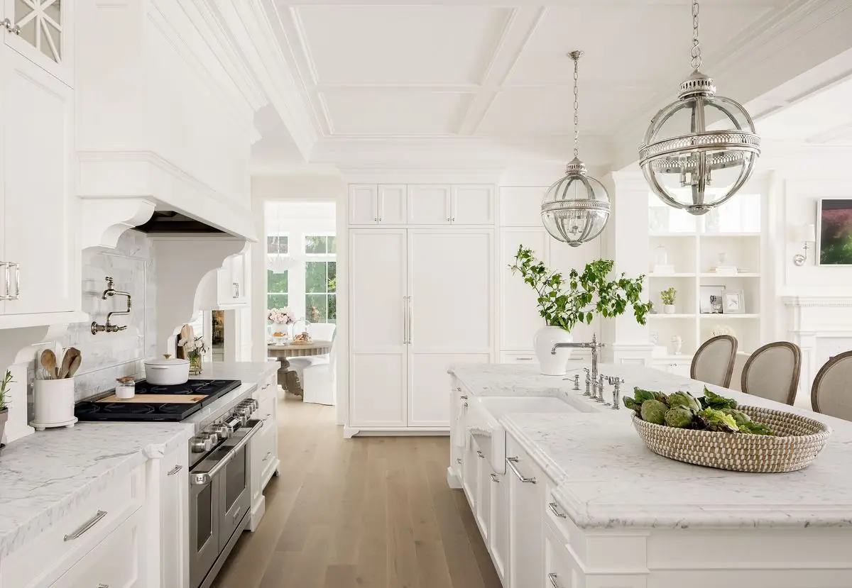 Range and island under globe pendants in the white kitchen