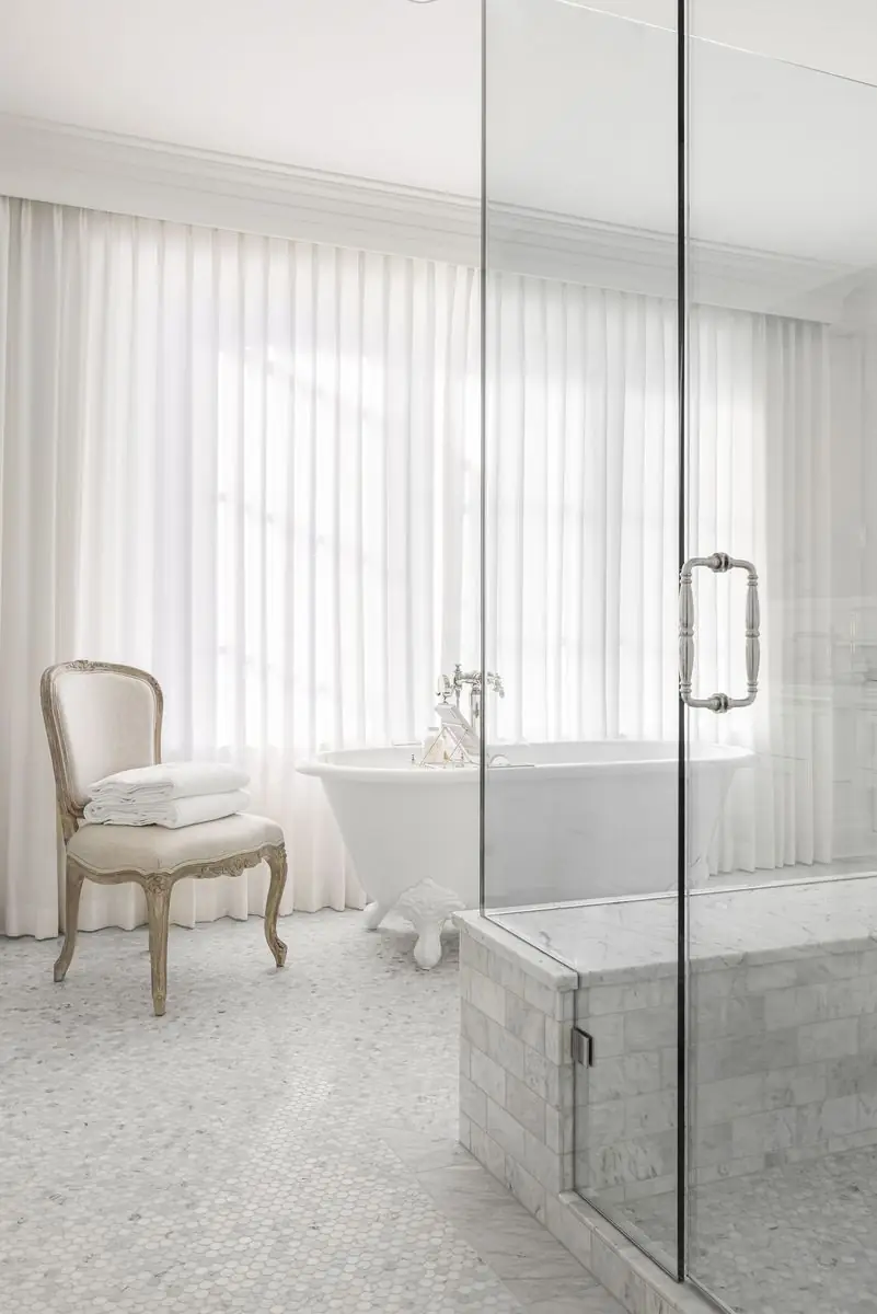 Ensuite with a freestanding tub behind sheer curtains