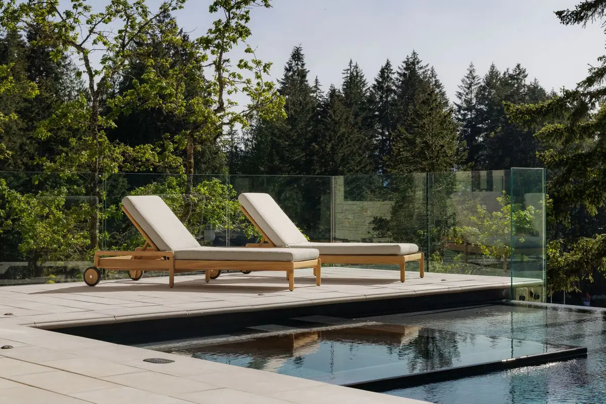 Loungers on the pool deck behind the glass railing