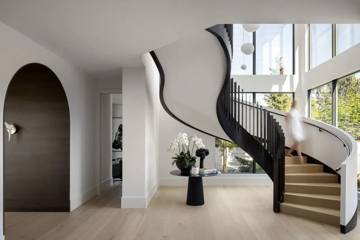 Curved stair rising from the entry, beside an arched door