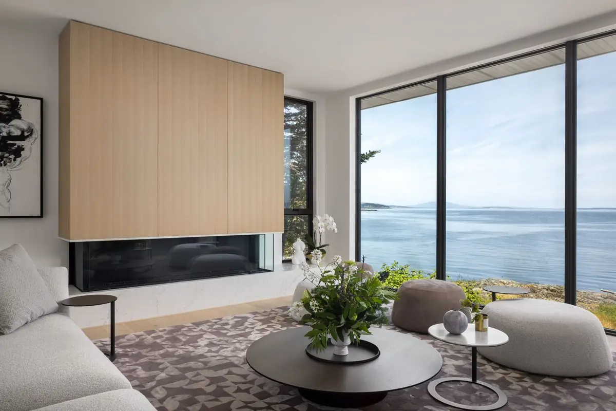 Living room with an oak-clad fireplace wall and the sea beyond