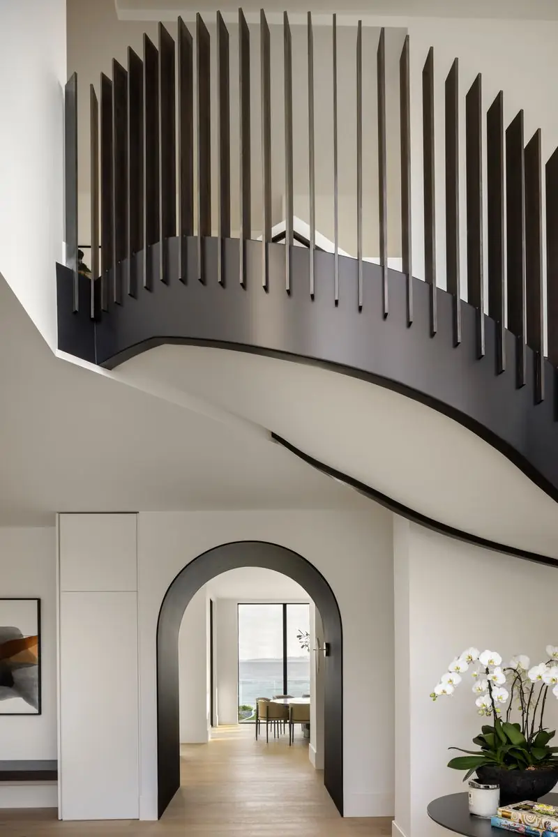 Under the curved stair, an arched opening to the hall
