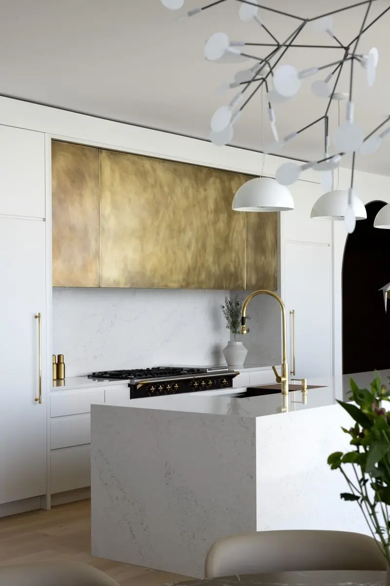 Brass range hood and a white stone island