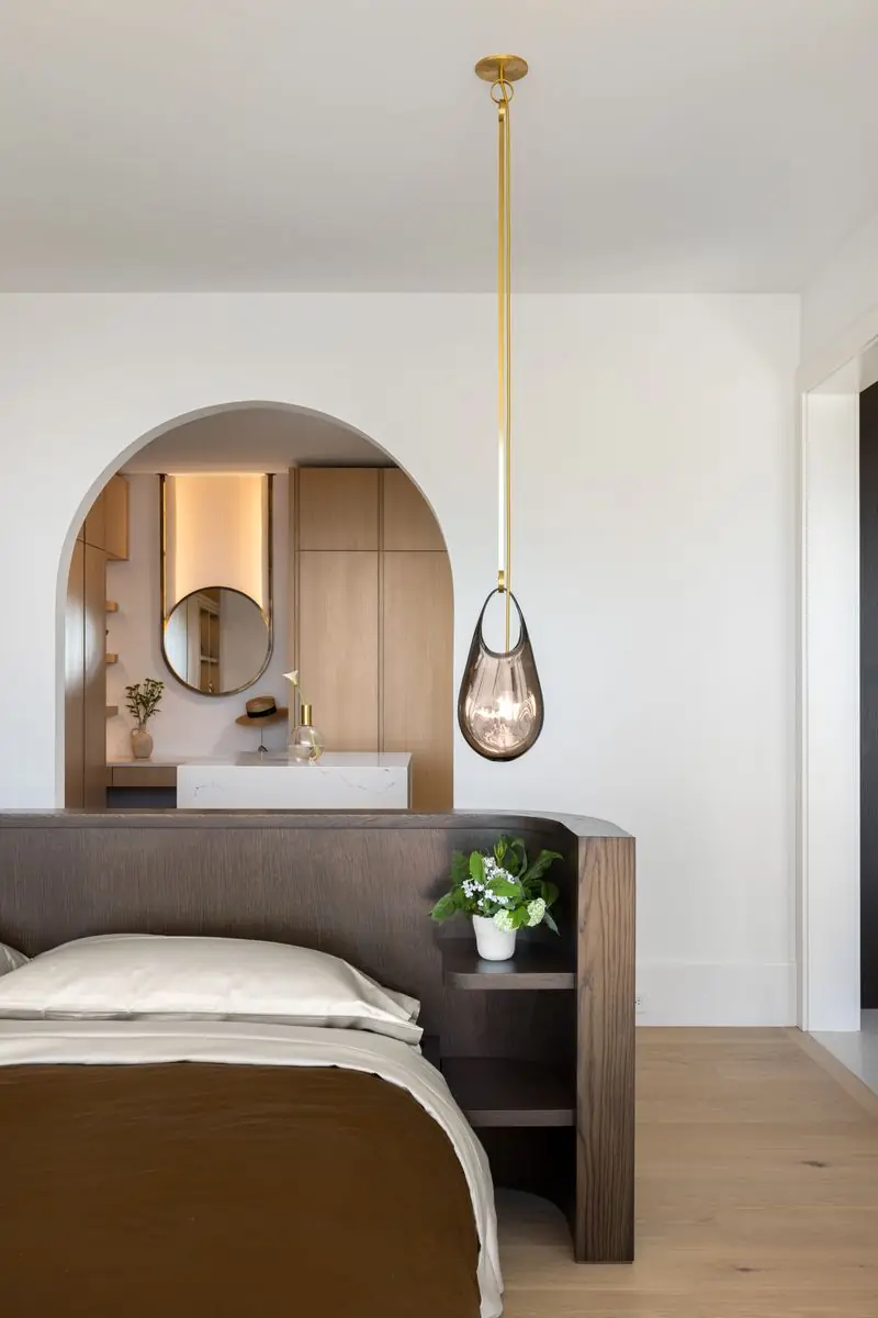 Bedroom with a glass pendant and an arched vanity niche behind the bed