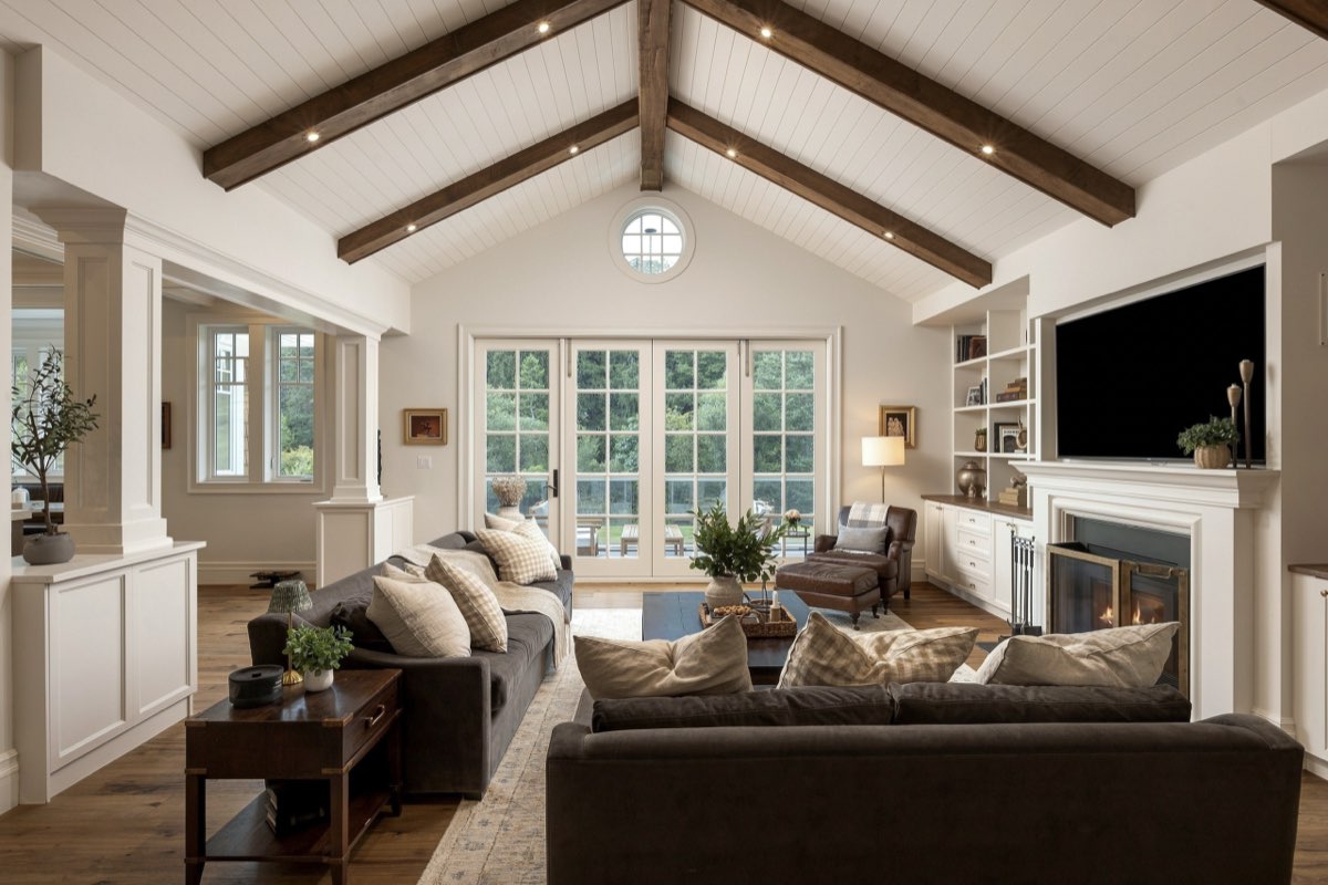 A living room under exposed beams, a deep sectional facing a wall of glass.