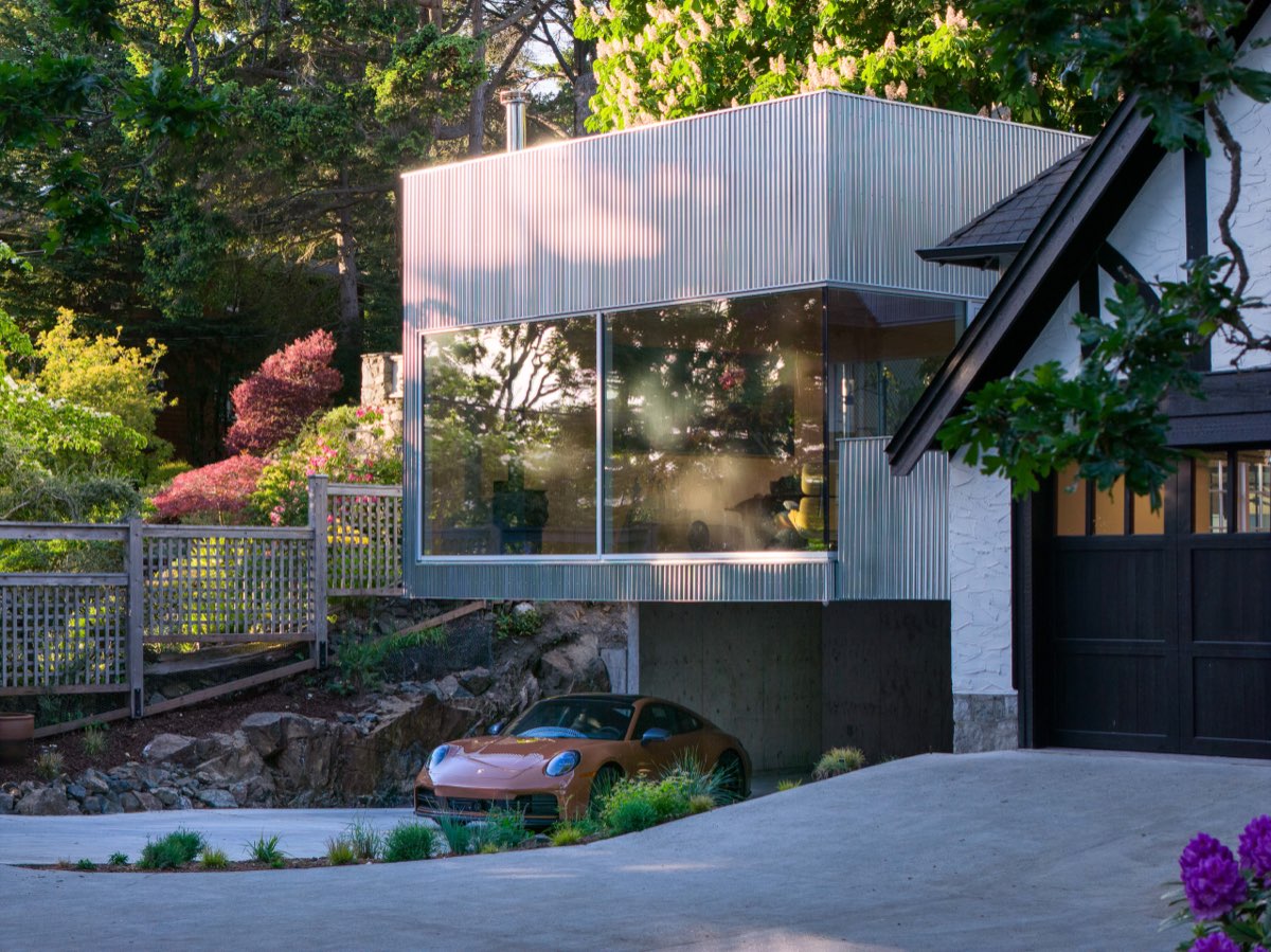 A modern elevation in glass and render seen across a planted garden.