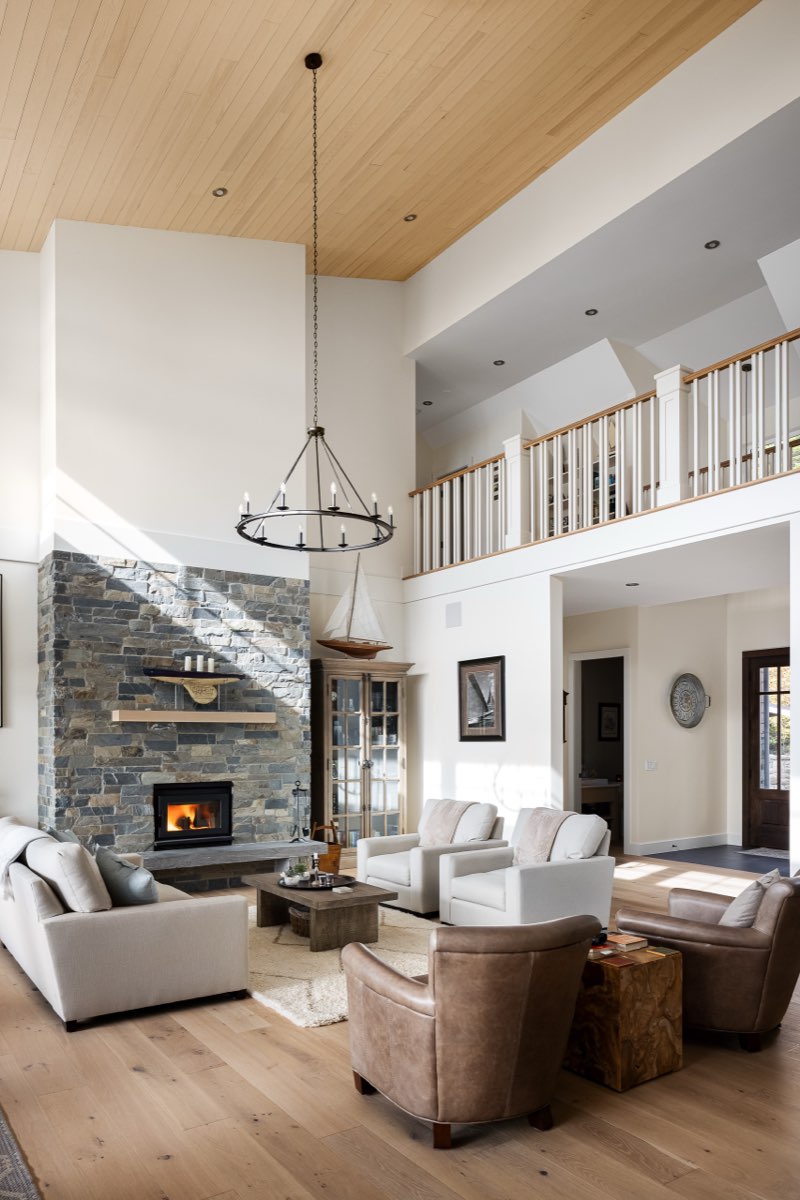 A double-height great room with a stone hearth and a long view